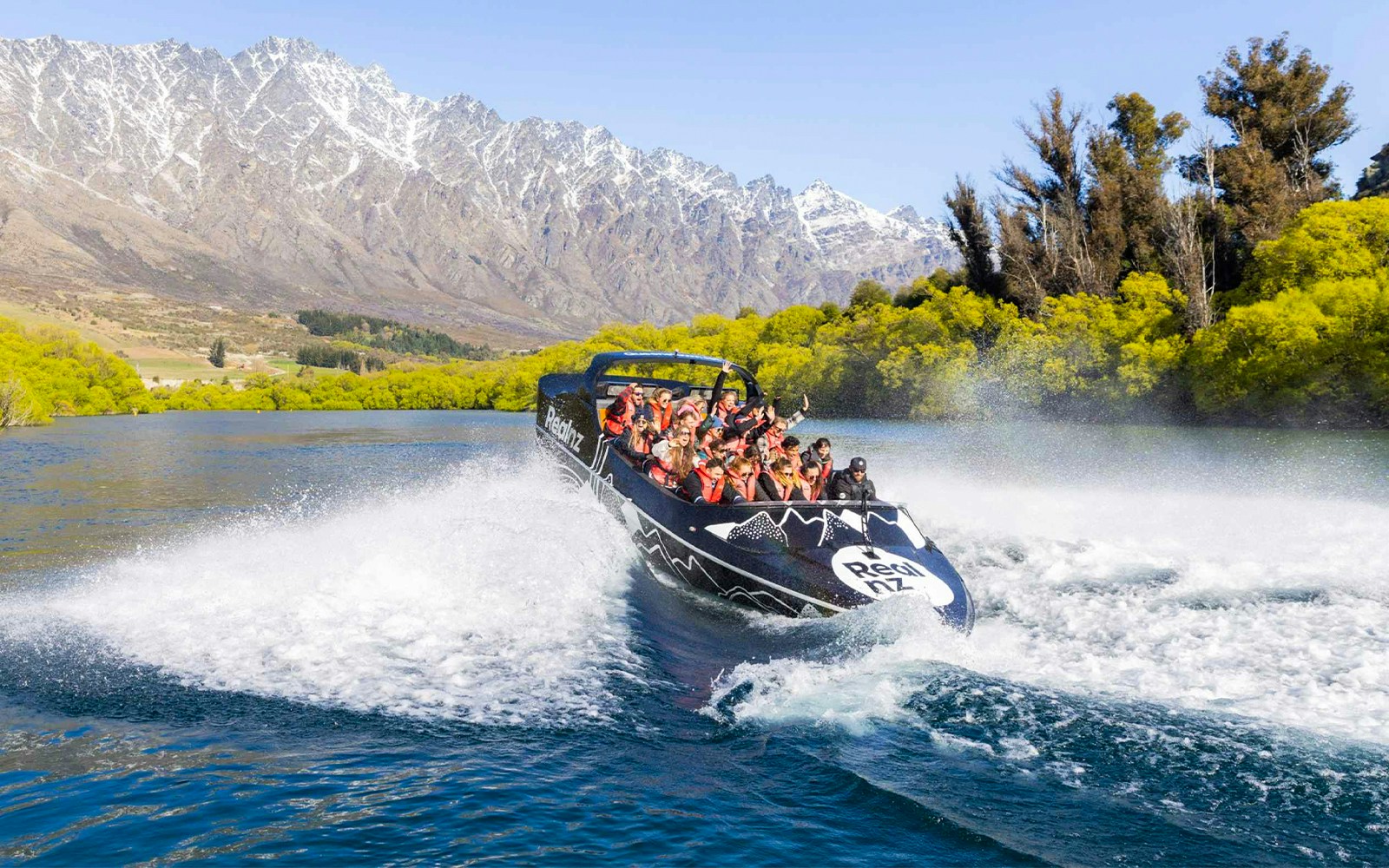 Jet boat navigating Kawarau River rapids with passengers in Queenstown, New Zealand.