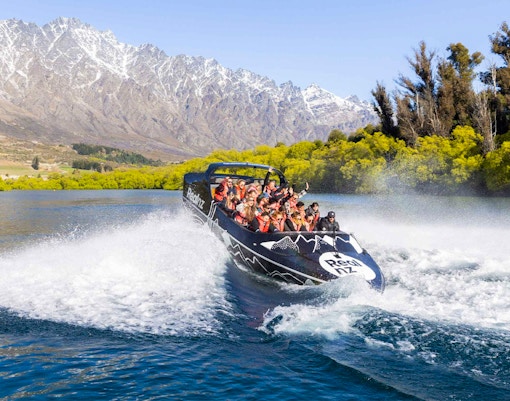 Jet boat navigating Kawarau River rapids with passengers in Queenstown, New Zealand.