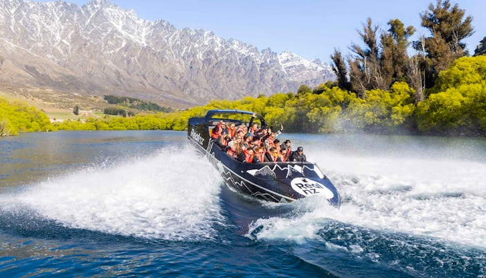 Jet boat navigating Kawarau River rapids with passengers in Queenstown, New Zealand.