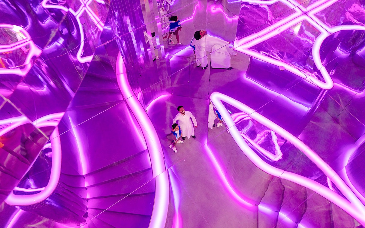 Visitors exploring neon-lit mirrored room at House of Hype.