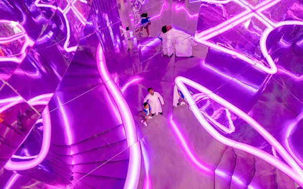 Visitors exploring neon-lit mirrored room at House of Hype.