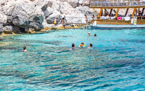 People swimming near a boat on a guided tour to Lower Duden Waterfall, Antalya.