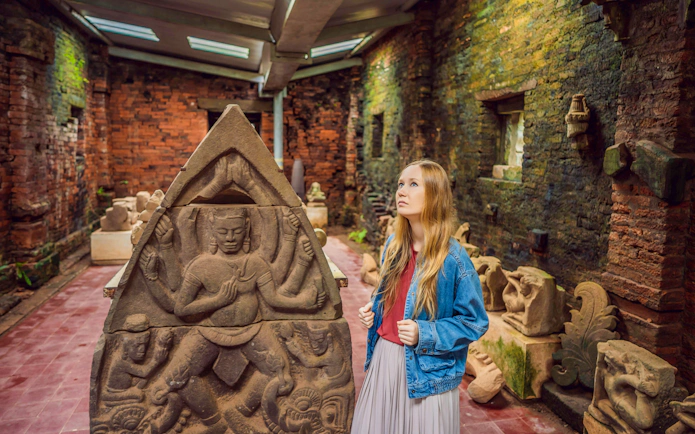 Tourist exploring ancient sculpture at My Son Sanctuary, Vietnam.