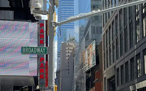Broadway street sign in Manhattan with tall buildings and billboards, New York City.