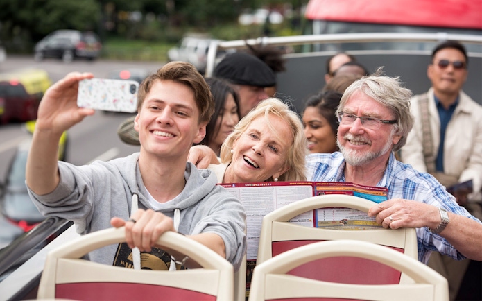 Family enjoying a ride on a HOHO Darwin tour bus, taking a selfie.