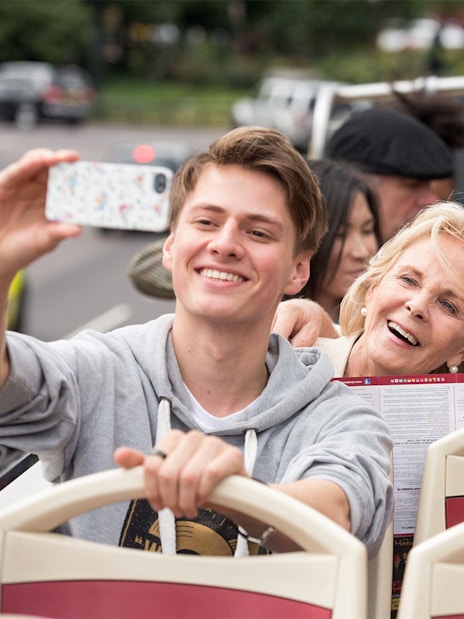 Family enjoying a ride on a HOHO Darwin tour bus, taking a selfie.