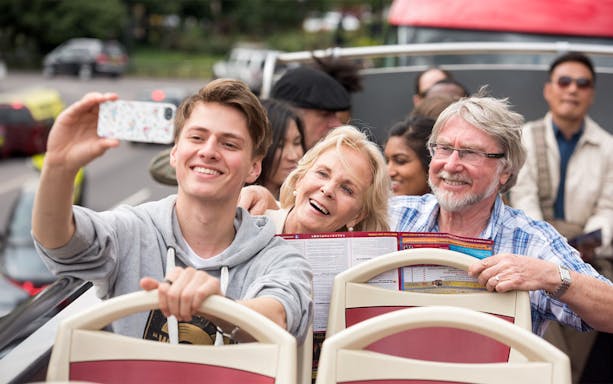 Family enjoying a ride on a HOHO Darwin tour bus, taking a selfie.