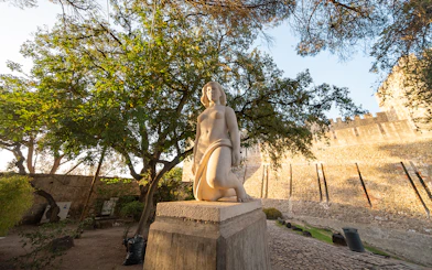 Statue in St George's Castle Gardens with trees and castle wall in Lisbon.