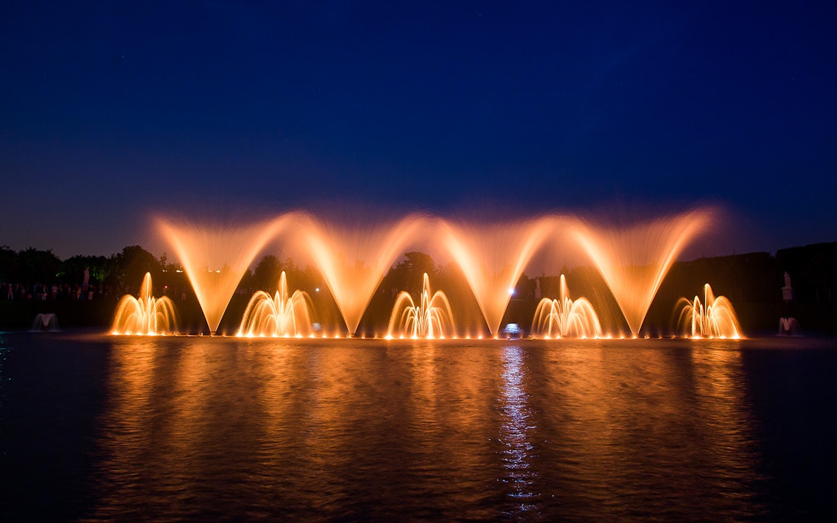 Fountain show at night in the Palace of Versailles gardens, France.