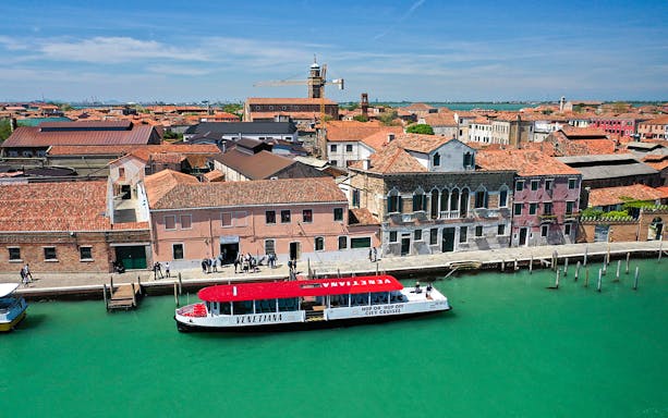 Panoramic view of a boat tour at Murano Island, Venice, with historic buildings along the canal.
