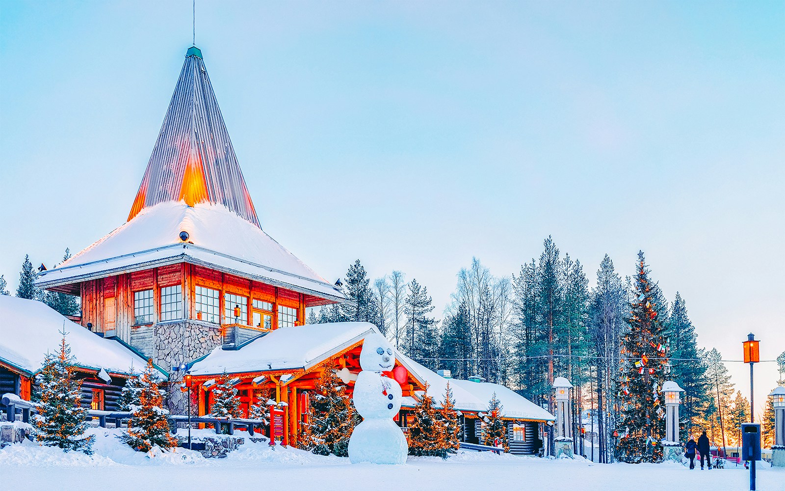 Snow-covered Santa Claus Village in Rovaniemi, Finland with a large snowman and Christmas tree.