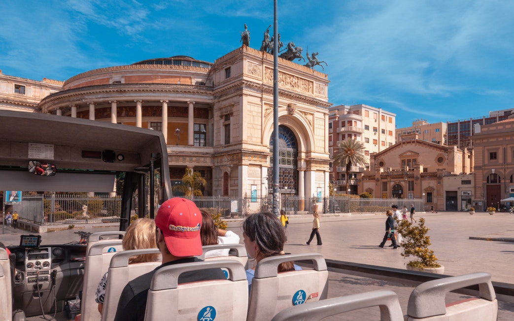 Sightseeing bus passengers view Teatro Politeama in Palermo.
