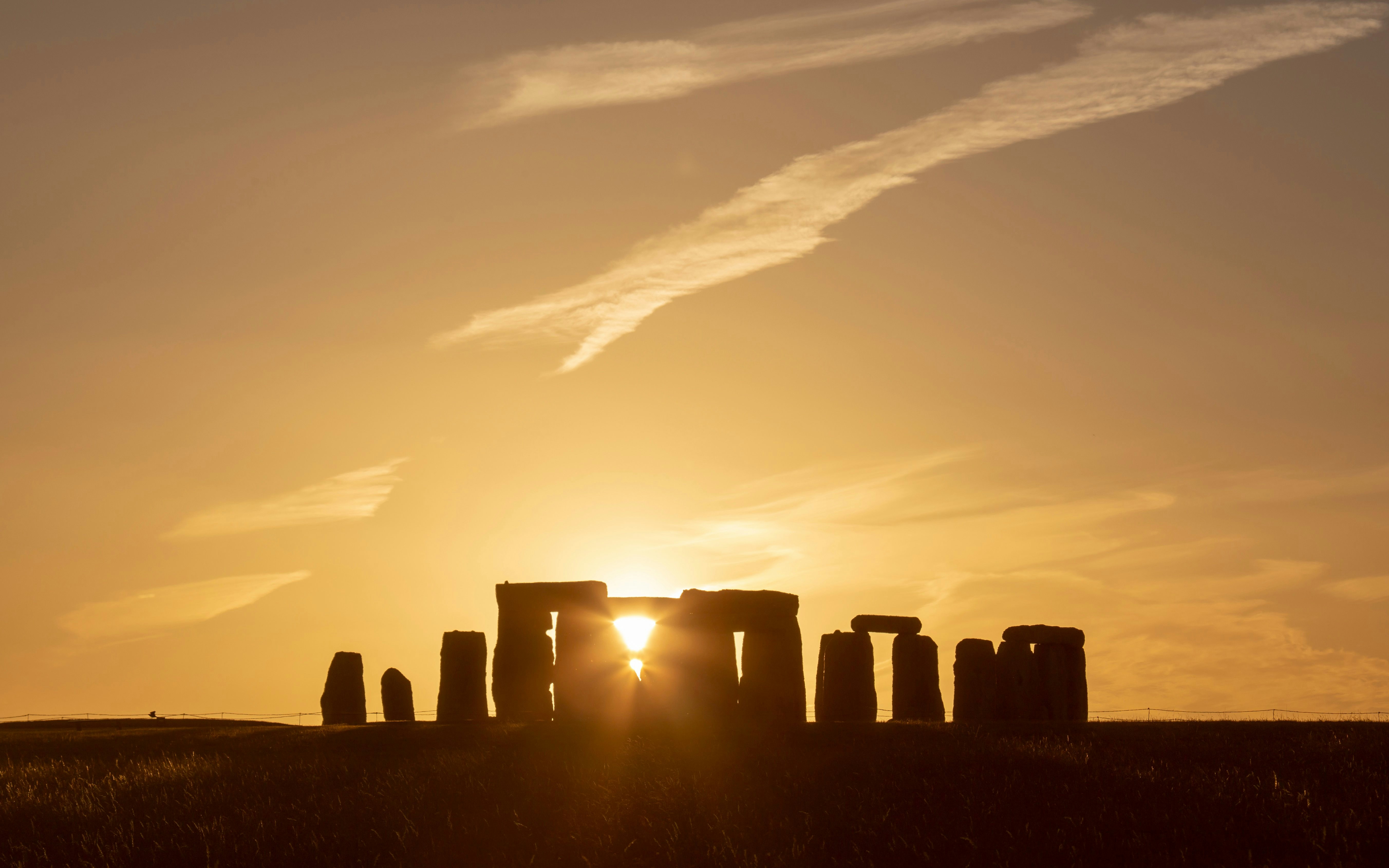 Stonehenge silhouetted against a sunset during the Summer Solstice in the UK.