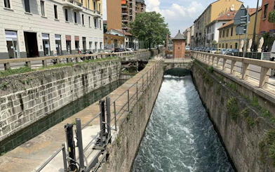 Navigli canal in Milan with historic buildings and a small bridge.