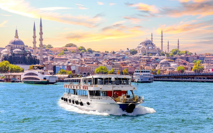 Bosphorus cruise ship sailing with Istanbul skyline and mosques in the background.