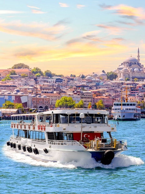 Bosphorus cruise ship sailing with Istanbul skyline and mosques in the background.
