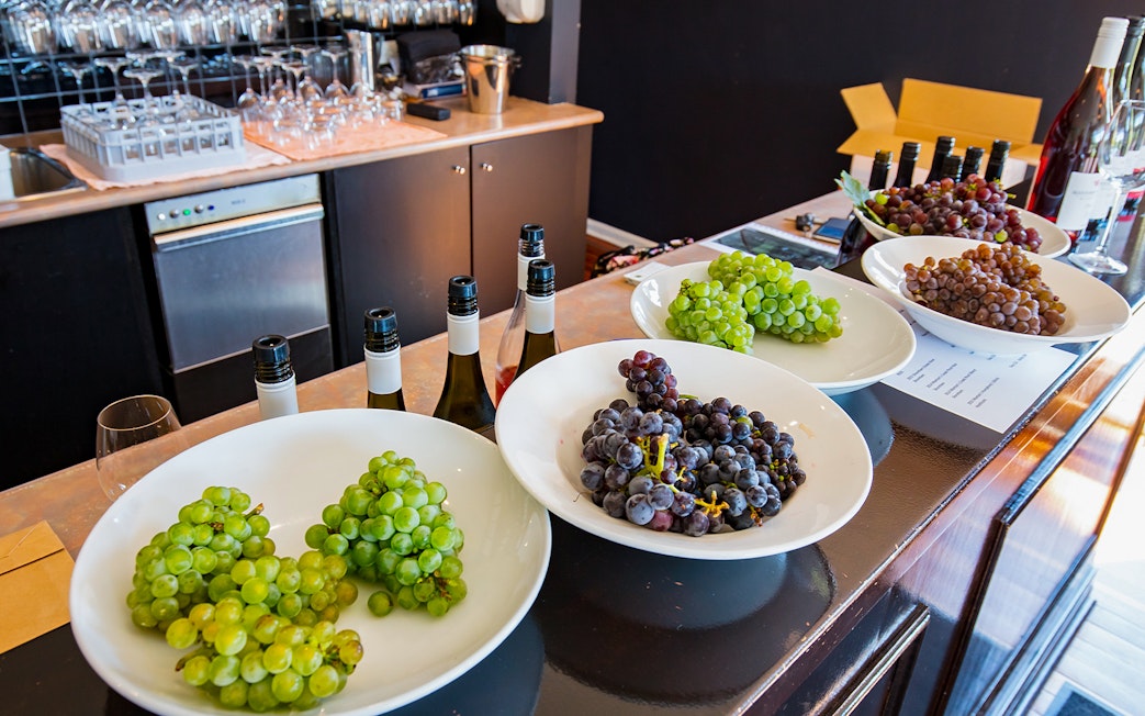 Grapes and wine bottles on a counter at Mornington Peninsula distillery tour.