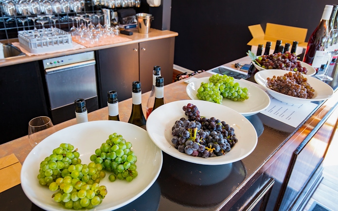 Grapes and wine bottles on a counter at Mornington Peninsula distillery tour.