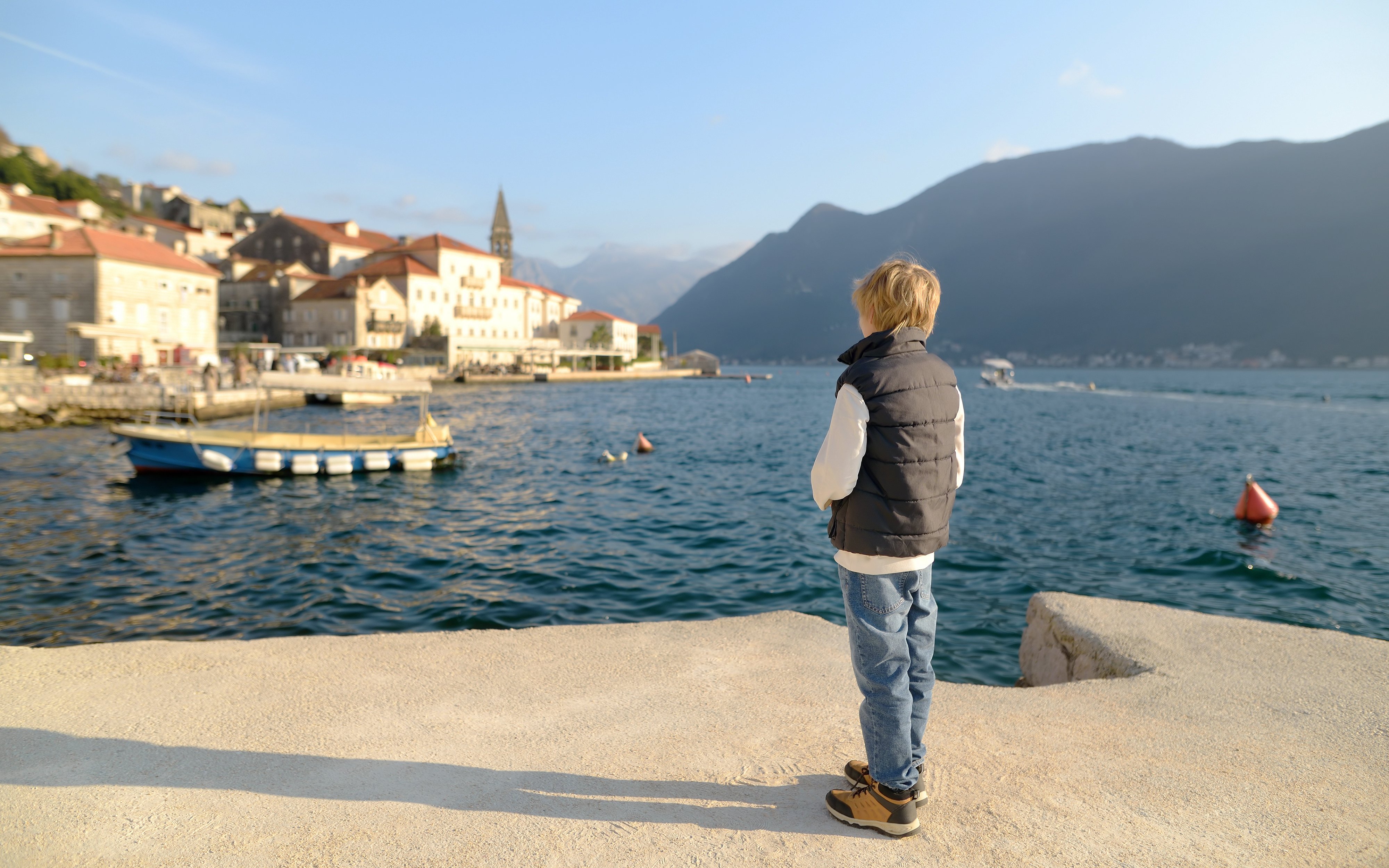 Child gazing at the historic waterfront of Perast, Montenegro.