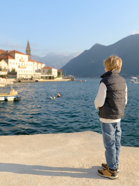 Child gazing at the historic waterfront of Perast, Montenegro.