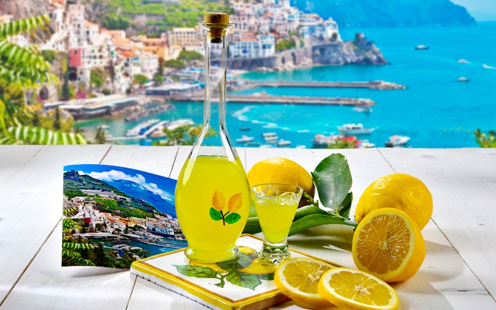 Limoncello bottle with lemons and Positano view, Rome to Positano tour.