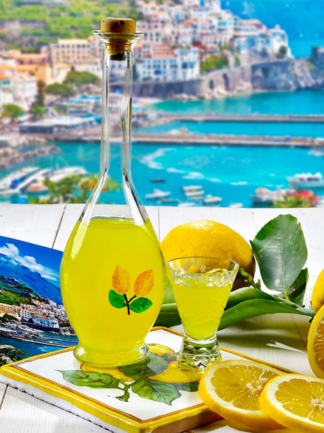 Limoncello bottle with lemons and Positano view, Rome to Positano tour.