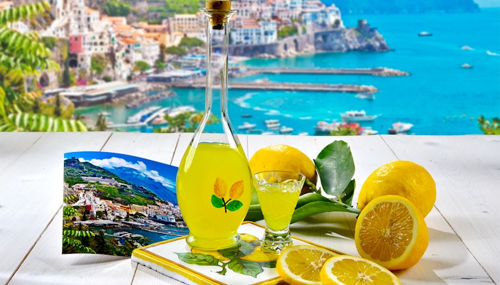 Limoncello bottle with lemons and Positano view, Rome to Positano tour.