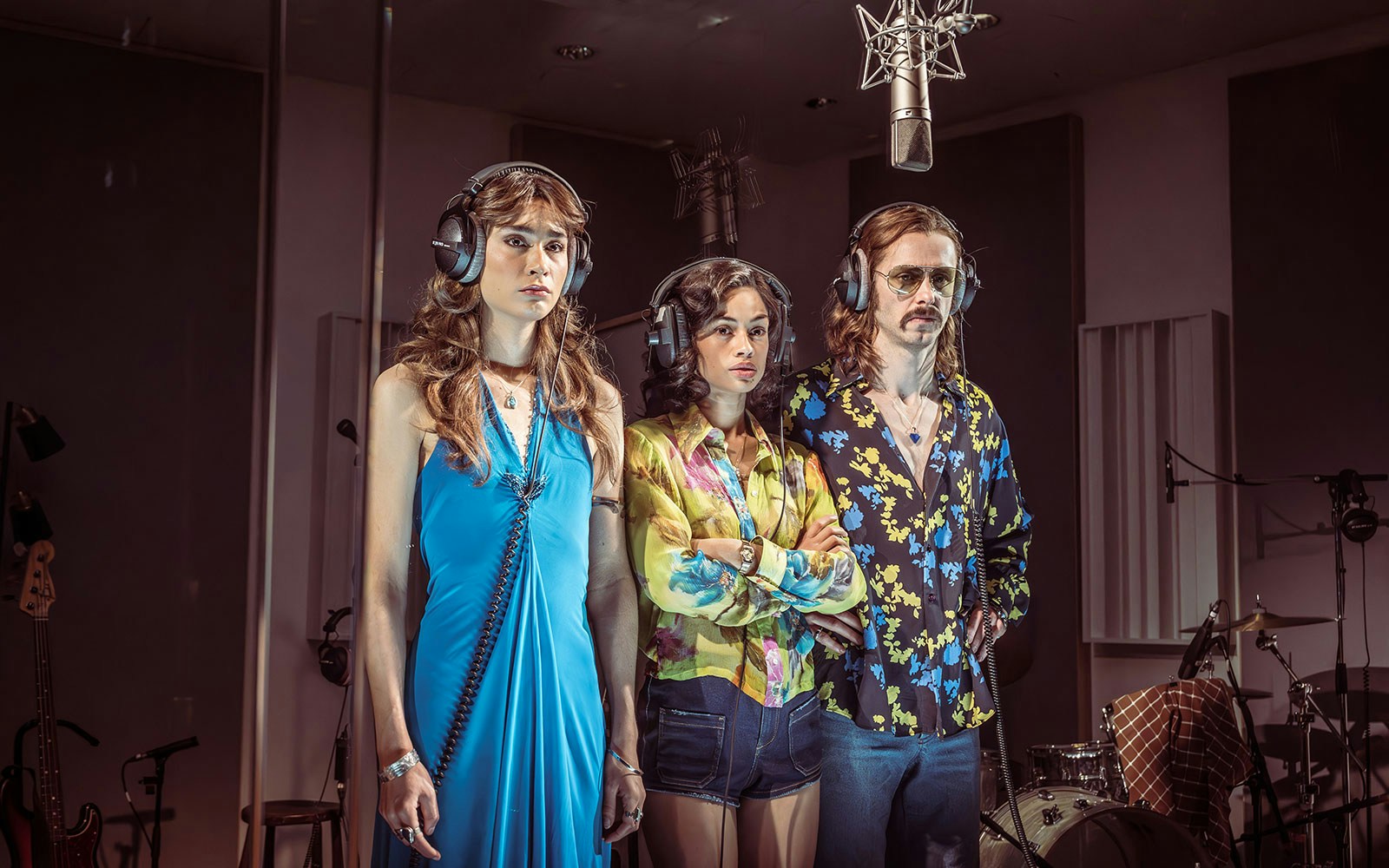 Three people wearing headphones in a recording studio with microphones, related to Stereophonic.