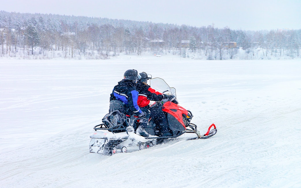 Snowmobile riders on a frozen lake in winter, Lapland.