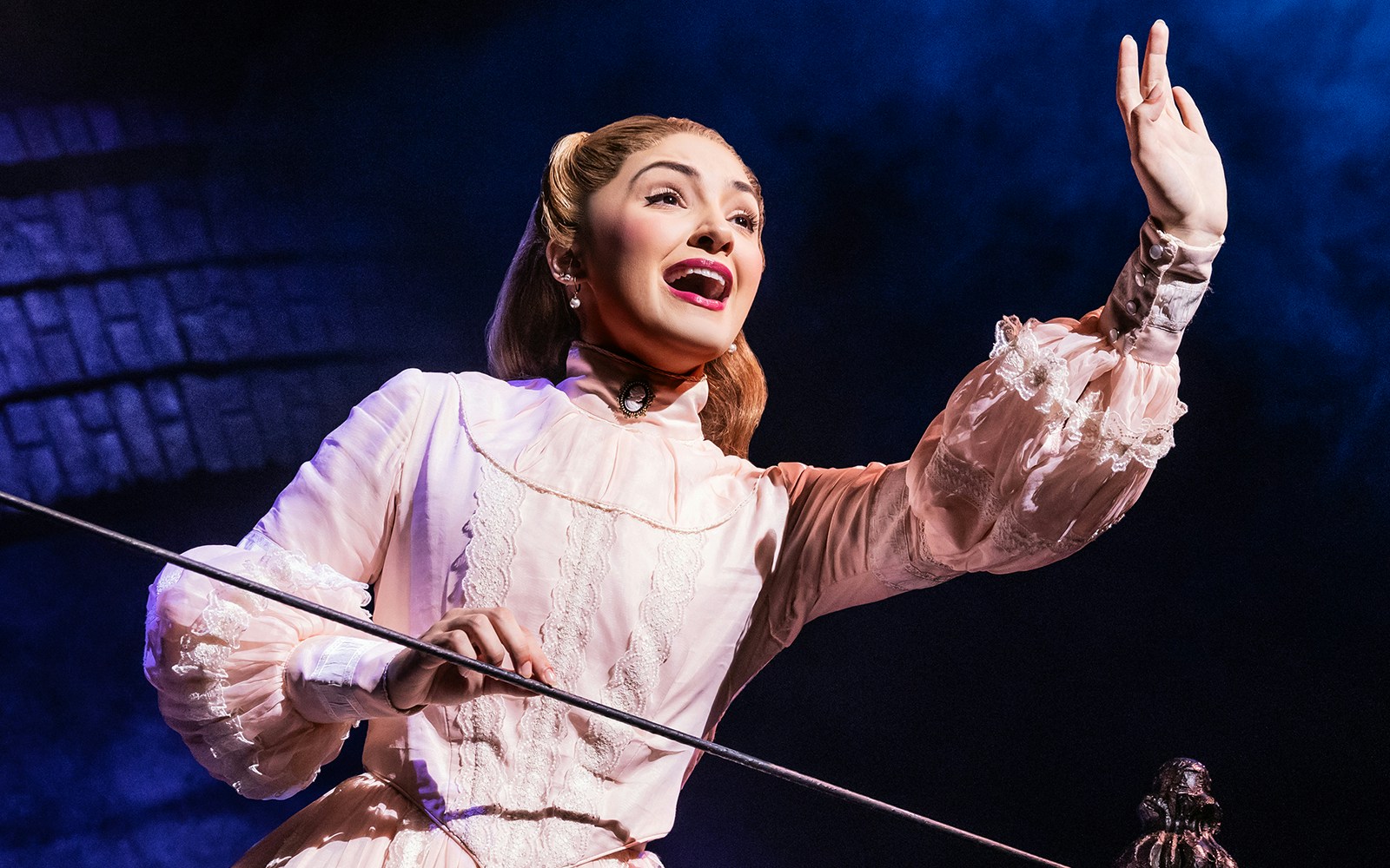 Performer in period costume singing on stage in Sweeney Todd production.