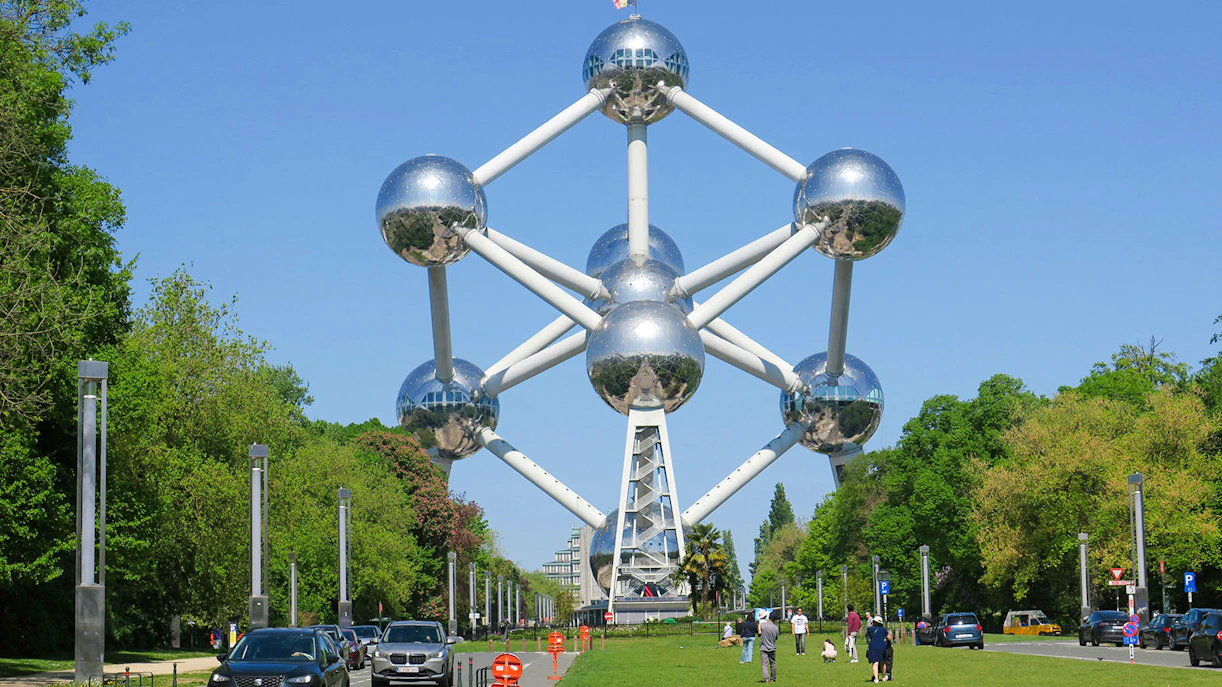 Atomium structure in Brussels with visitors and cars nearby.