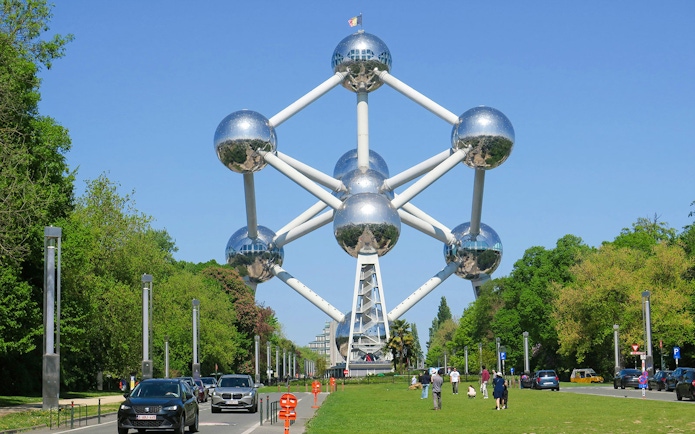Atomium structure in Brussels with visitors and cars nearby.
