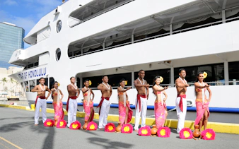 Hula dancers in traditional attire in front of the Star of Honolulu cruise ship, Hawaii.