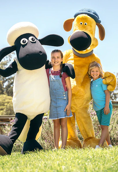 Children posing with farm animal mascots at Paradise Country Farmstay.