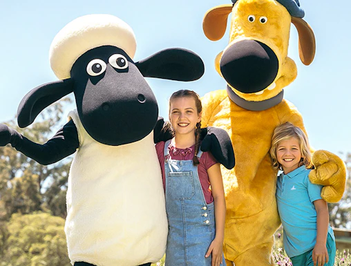 Children posing with farm animal mascots at Paradise Country Farmstay.