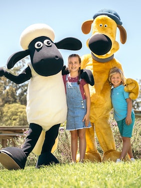 Children posing with farm animal mascots at Paradise Country Farmstay.