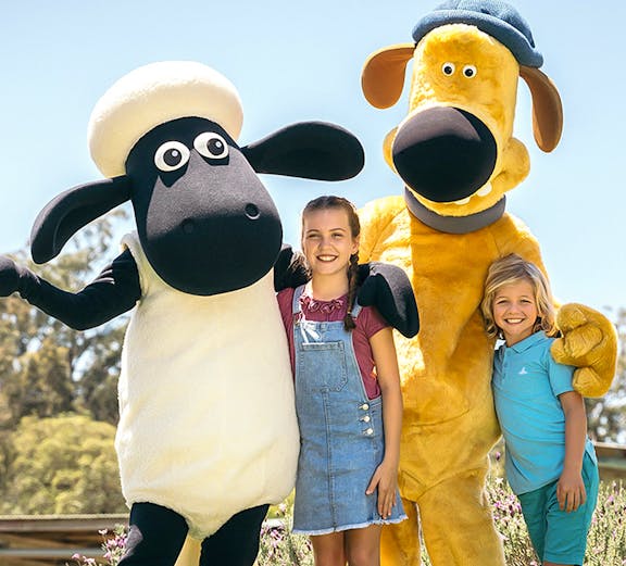 Children posing with farm animal mascots at Paradise Country Farmstay.