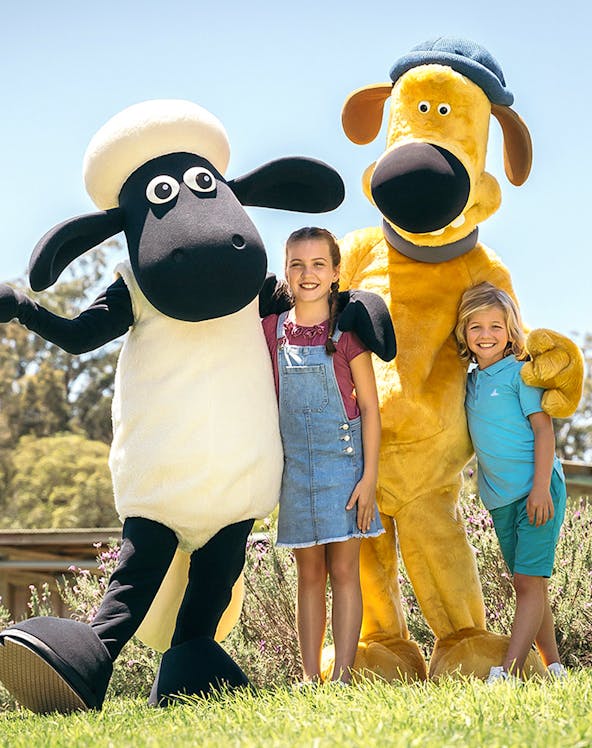 Children posing with farm animal mascots at Paradise Country Farmstay.
