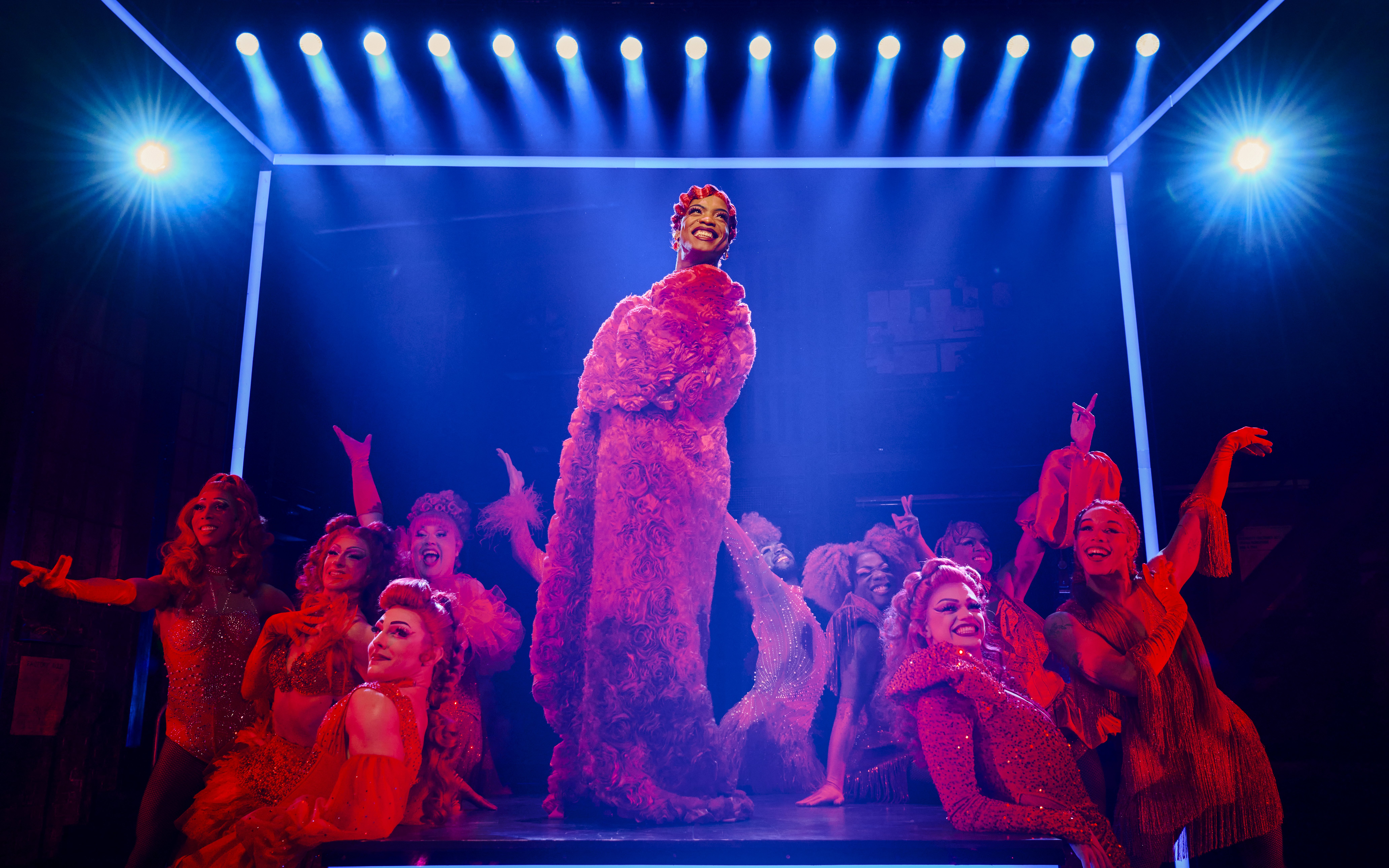 Performers in vibrant costumes on stage during a Kinky Boots production.