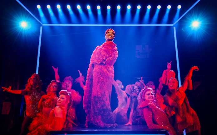 Performers in vibrant costumes on stage during a Kinky Boots production.