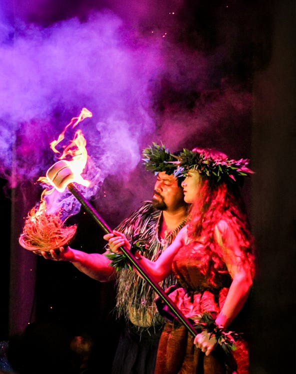 Performers at Moana Luau in Hawaii holding a flaming torch during a traditional Hawaiian ceremony.
