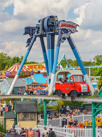 Drayton Manor theme park ride with red train and Maelstrom attraction in background.