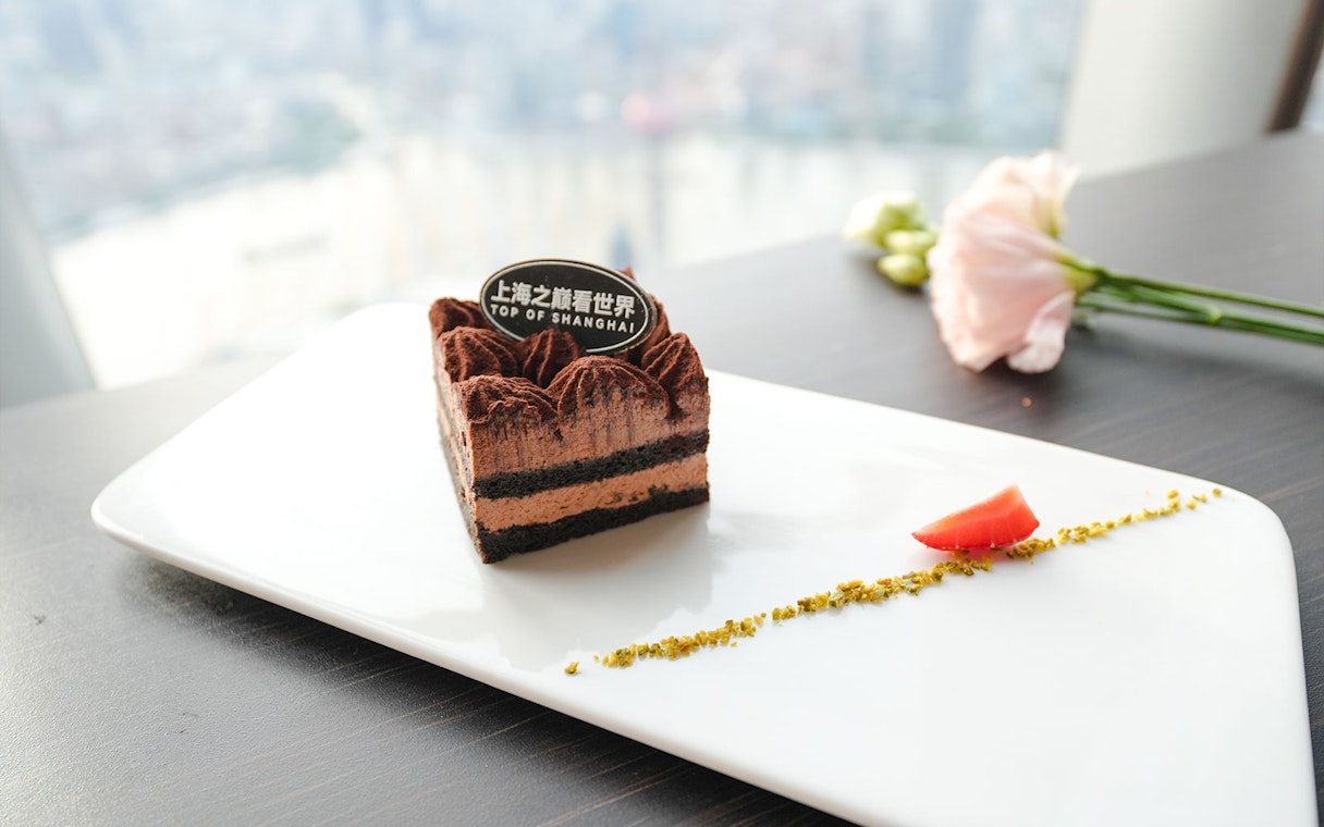 Chocolate dessert at Shanghai Tower restaurant with city view.