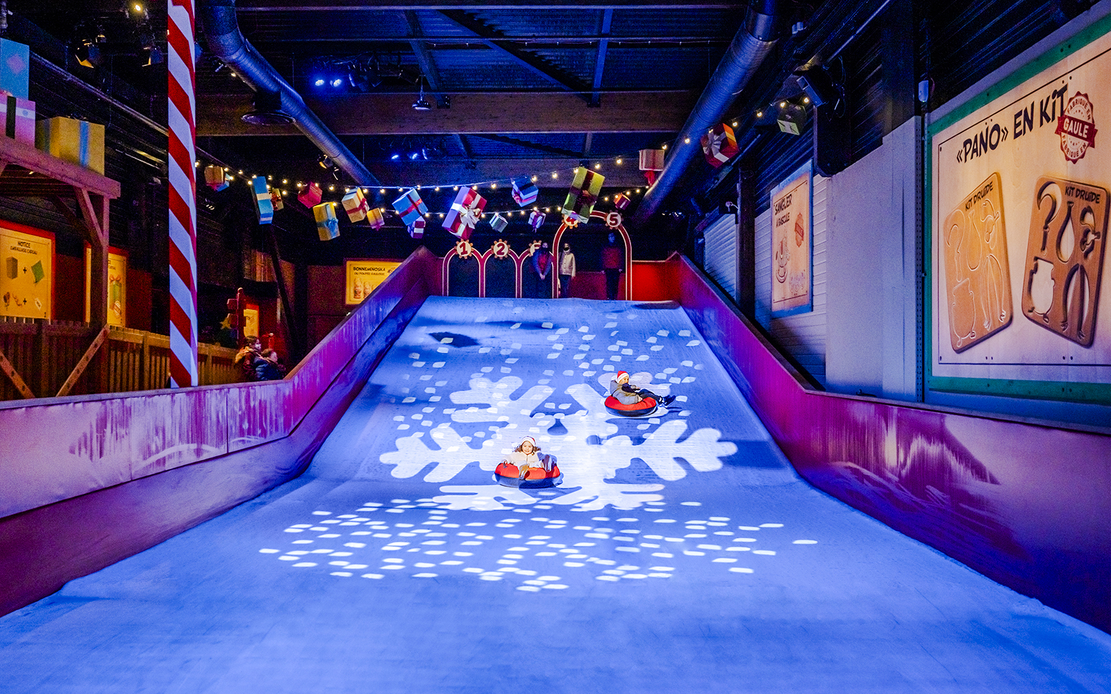 Children sledding indoors at Parc Asterix during Christmas celebrations.