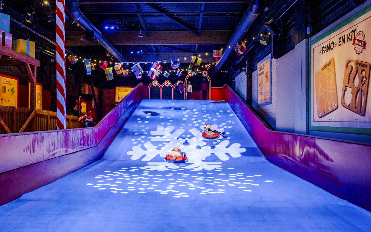 Children sledding indoors at Parc Asterix during Christmas celebrations.