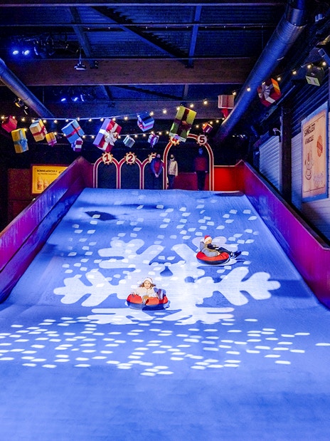 Children sledding indoors at Parc Asterix during Christmas celebrations.