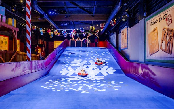 Children sledding indoors at Parc Asterix during Christmas celebrations.