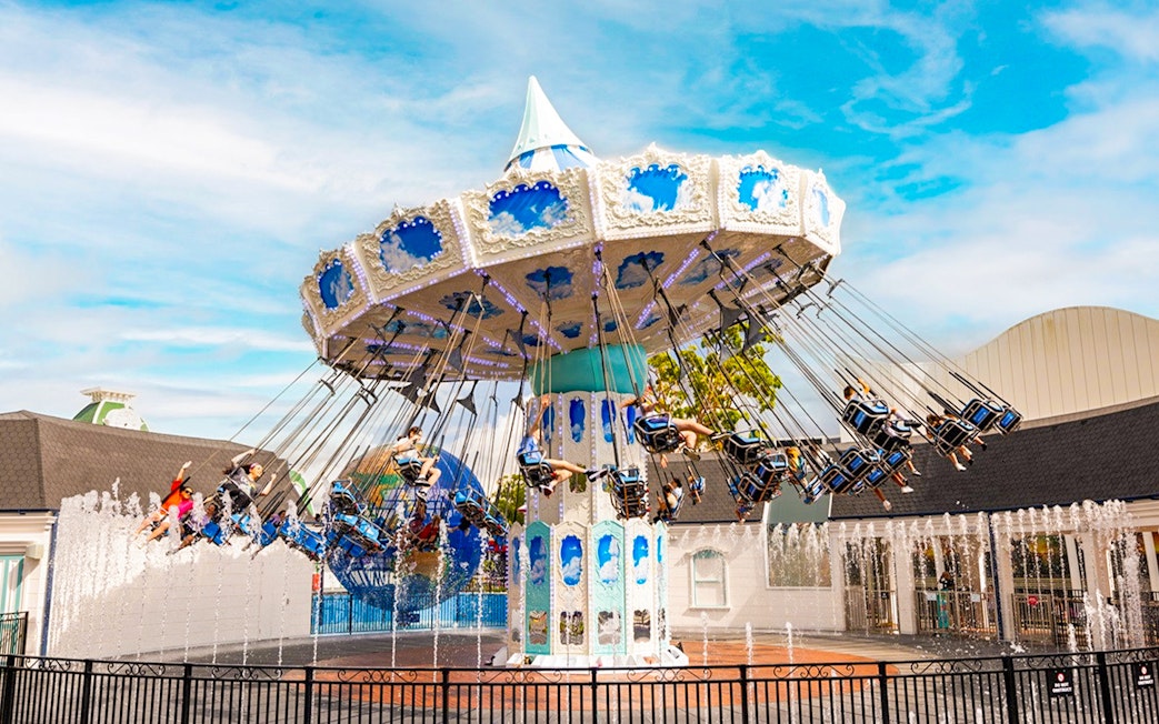 People enjoying a carousel ride at Dreamworld with fountains in the foreground.