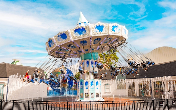 People enjoying a carousel ride at Dreamworld with fountains in the foreground.