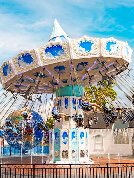 People enjoying a carousel ride at Dreamworld with fountains in the foreground.